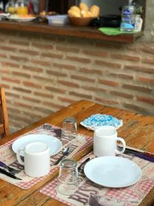 uma mesa de madeira com pratos e copos brancos em Pousada kaz'oca em Icaraí
