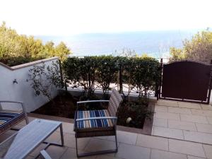 un patio con mesa, sillas y el océano en Greta en Castelsardo
