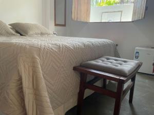 a bedroom with a bed with a stool next to it at Pousada Ecó Milagres - Praia in São Miguel dos Milagres