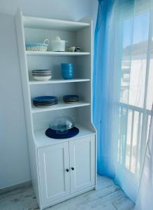 a white cabinet with plates and dishes on it at Blue House Mallorca in Ses Salines