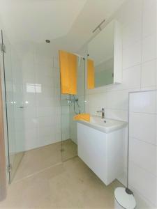 a white bathroom with a sink and a mirror at Apartment Sonnenschein in Dornbirn