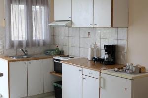 una pequeña cocina con armarios blancos y fregadero en Flo's Apartments, en Mesolongi
