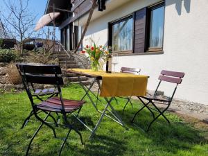 a table with three chairs and a vase of flowers on it at Apartment Sonnenschein in Dornbirn