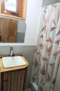a bathroom with a sink and a shower curtain at La Cantonada in Caviahue