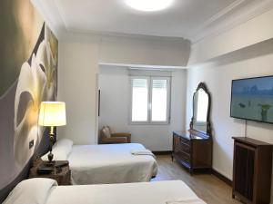 Habitación de hotel con 2 camas y TV de pantalla plana. en Hostal La Mexicana, en Santander
