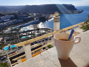 a cup of coffee sitting on the ledge of a balcony at Apartamentos Monseñor in Playa del Cura