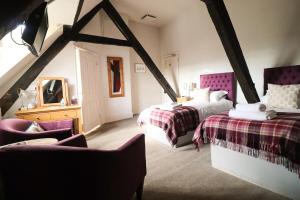 a attic bedroom with two beds and a chair at The Castle Hotel in Bishops Castle
