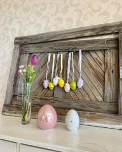 a wooden frame with easter eggs and a vase with flowers at Divá Kačica Restaurant & Pansion in Komárno