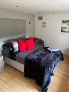 um quarto com uma cama grande e almofadas vermelhas em The Glen Guest House 1-bedroom guest house with free parking em Fyfield