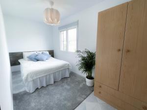 Dormitorio blanco con cama y maceta en La Zenia Beach House, en Alicante