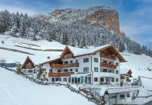 a hotel in the snow with a mountain in the background at Garni Sunela B&B in Selva di Val Gardena