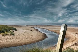 a view of a beach with a wooden post at Mussenden House in Articlave +3 photos
