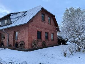 a red brick house with snow on the ground at Ferienwohnung Familie Görtler in Graal-Müritz