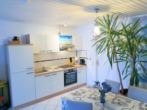 a kitchen with white cabinets and a table and a plant at Käpt'n Böff in Vadersdorf