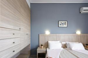 1 dormitorio con paredes azules y 1 cama con almohadas blancas en Yiannis Apartments, en Adelianos Kampos
