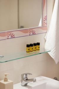 a bathroom with a sink and a shelf with five jars at Yiannis Apartments in Adelianos Kampos