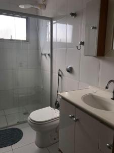 uma casa de banho com um chuveiro, um WC e um lavatório. em Apartamento quadra da praia - Pitangueiras Guarujá no Guarujá