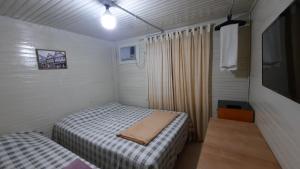 Habitación pequeña con 2 camas y TV. en Pousada Recriare, en Campo Mourão