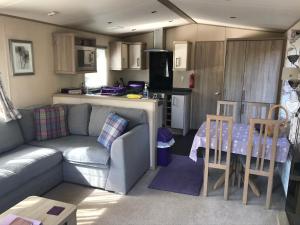 a living room with a couch and a table and a kitchen at Riverbank Lodge in Aviemore