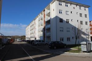 a large white building with cars parked in a parking lot at Apartman Cer in Banja Koviljača