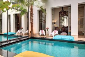 a swimming pool with chairs and a house at Riad Antara in Marrakech