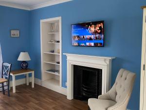 un salon avec une cheminée et une télévision au-dessus. dans l'établissement Ballachulish House Apartment, à Ballachulish