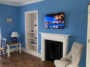 a living room with a fireplace with a tv above it at Ballachulish House Apartment in Ballachulish
