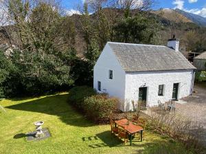 a small white house with a table in the yard at The Bothy of Ballachulish House in Ballachulish