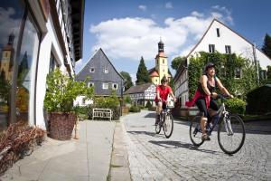 Dos personas en bicicleta por una calle en Ferienwohnung Feel Good Apartment - zentrale 65qm Design Fewo im Zittauer Gebirge - bahnhofsnah in ruhiger Lage, en Zittau