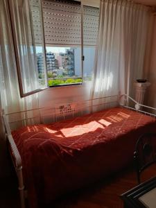 Un dormitorio con una cama roja con una ventana. en Hosp Italiano cómodo equipado con piano luz y sol Bienvenidos!, en Buenos Aires