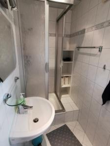 uma casa de banho branca com um chuveiro e um lavatório. em Bungalow Ulf em Lauchhammer