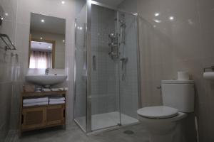 uma casa de banho com um chuveiro, um WC e um lavatório. em Hostal Restaurante Goya em Piedrahita