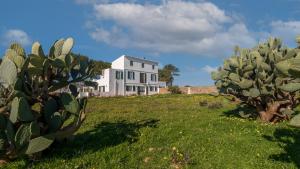 una casa blanca en una colina con cactus en Agroturismo Son Rosas, en Ciutadella