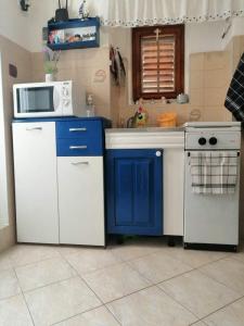 eine Küche mit blauen und weißen Schränken und einer Mikrowelle in der Unterkunft ANCHOR BAŠKA in Baška