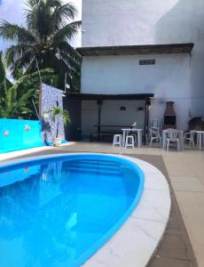 a swimming pool in front of a house with a table and chairs at Casa alto da Boa Vista in Maragogi