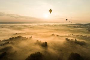 two hot air balloons flying over a fog covered field at White Apartment in Iwonicz-Zdrój