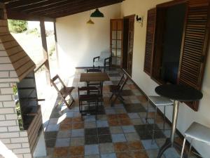 a room with a table and chairs on a patio at Chale no centro de Lumiar com água de nascente in Nova Friburgo