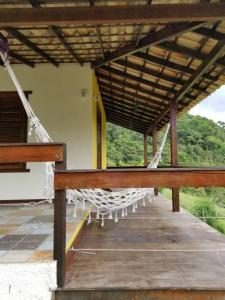 a porch with white chairs sitting under a roof at Chale no centro de Lumiar com água de nascente in Nova Friburgo