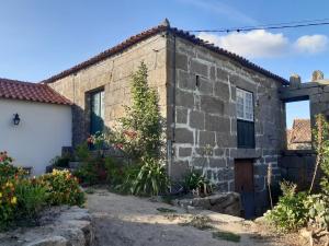 uma antiga casa de pedra com uma garagem branca em Casa em Resende com Vista Para o Rio Douro em Resende