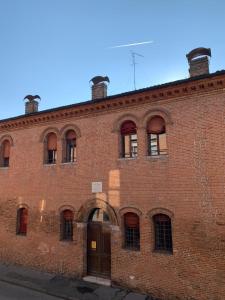 ein großes rotes Backsteingebäude mit einer Tür in der Unterkunft [Ferrara Centro - WABI APT] in Ferrara