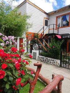 エル・カラファテにあるVidorra Calafateの赤いバラと木製のベンチのある家