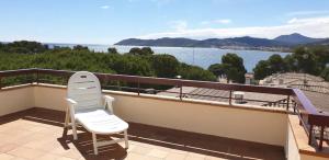 ein Paar weißer Stühle auf einem Balkon mit Blick auf das Wasser in der Unterkunft Preciosa casa con piscina de agua salada y aire acondicionado in Llança