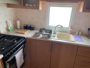 a kitchen counter with a sink and a stove at Lovely 3 bedroom 8 berth caravan in Rhyl in Rhyl