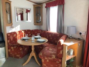 een woonkamer met een bank en een tafel bij Lovely 3 bedroom 8 berth caravan in Rhyl in Rhyl