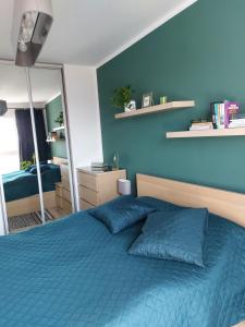 a blue bedroom with a bed and a mirror at Apartament przy stadionie in Gdańsk