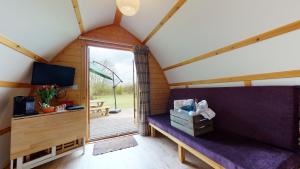 a room in a tiny house with a purple couch at Hill Farm and Orchard in Leighton Buzzard