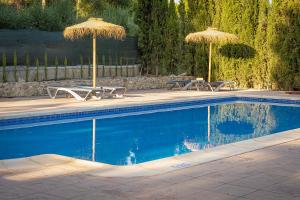 two picnic tables and umbrellas next to a swimming pool at Casas Rurales Caravaca de la Cruz in Caravaca de la Cruz