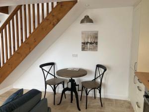 a table and chairs in a living room with a staircase at May Cottage in Bridlington