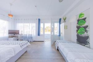 a white bedroom with two beds and a desk at Hôtel Land'Azur in Mimizan-Plage