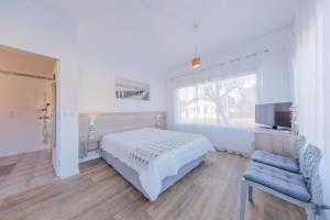 a bedroom with a bed and a tv and a chair at Hôtel Land'Azur in Mimizan-Plage